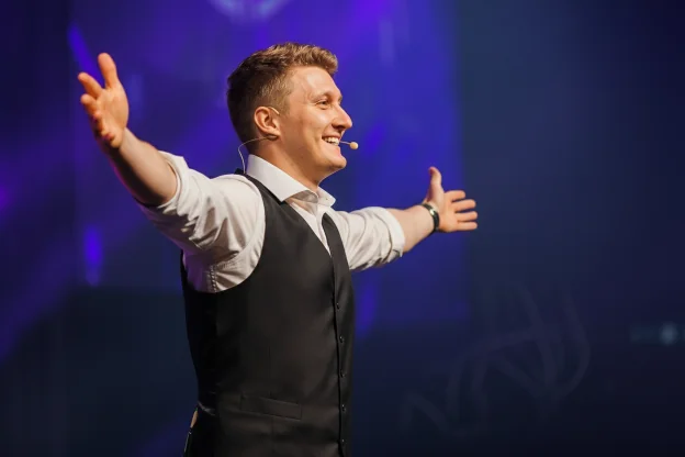 Magiske Daniel som konferansier strekker hendene mot publikum under firmaarrangement